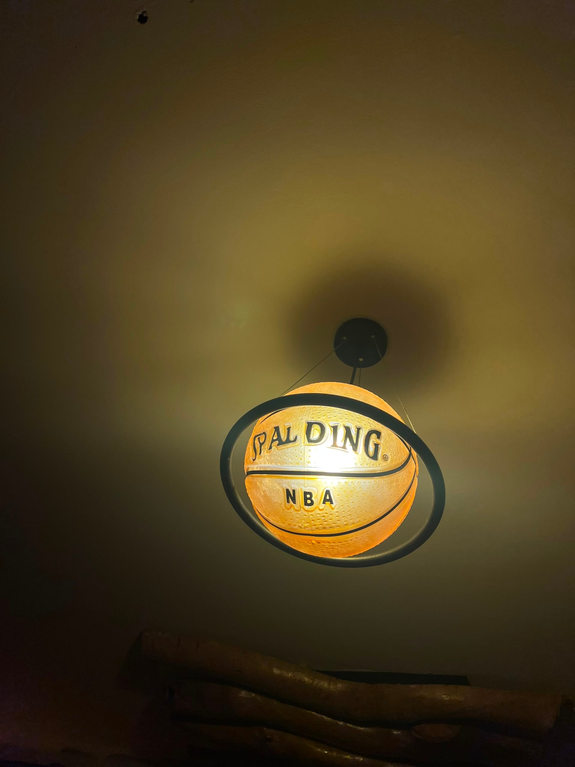 Glowing Spalding NBA basketball pendant lamp hanging from a ceiling