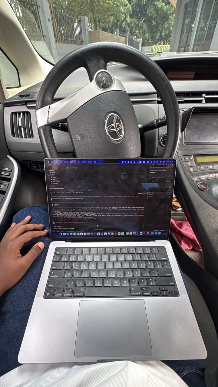 Person coding in VS Code on a laptop while sitting in the driver seat of a Toyota