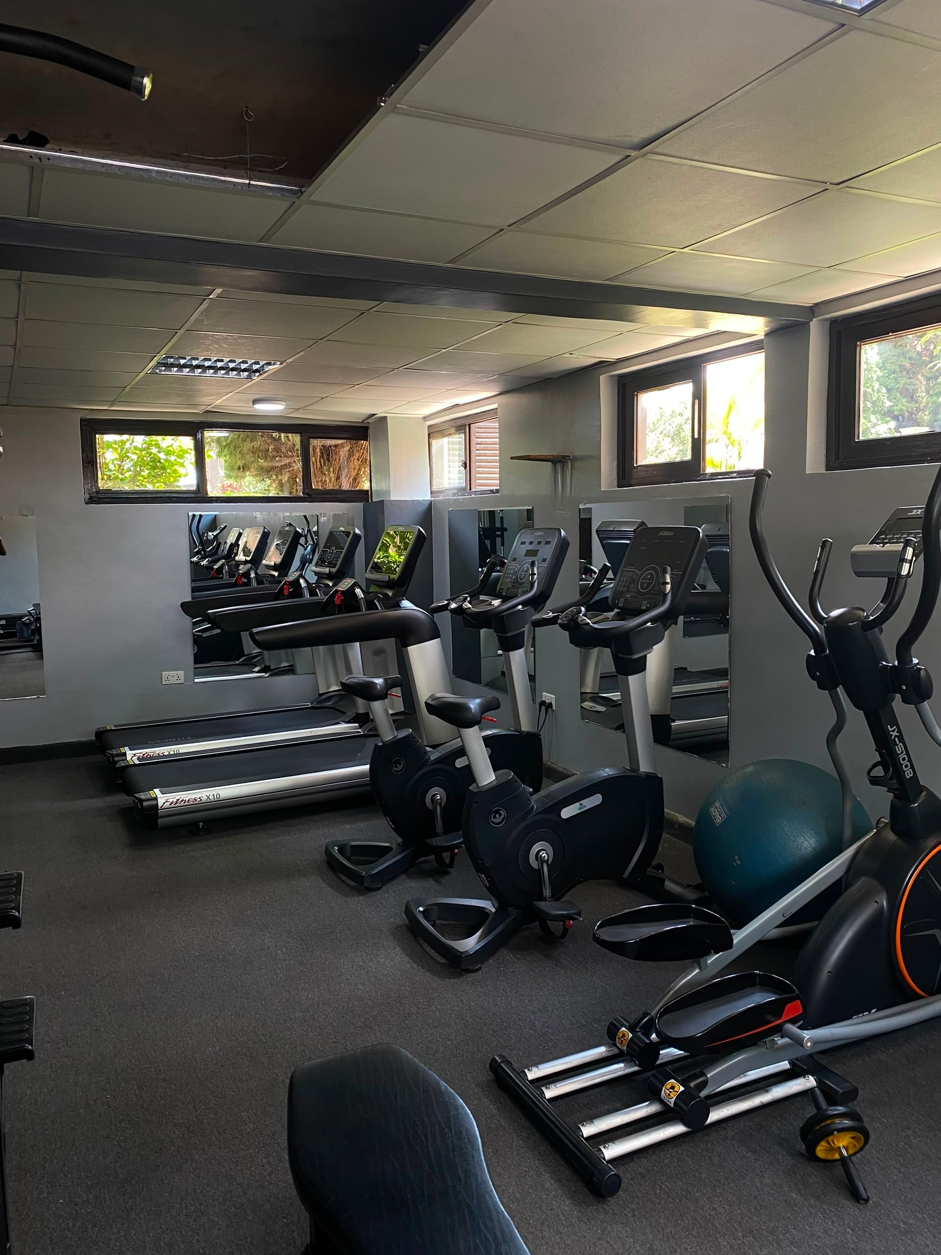 Indoor gym with treadmills, stationary bikes, and an elliptical lined along mirrored walls