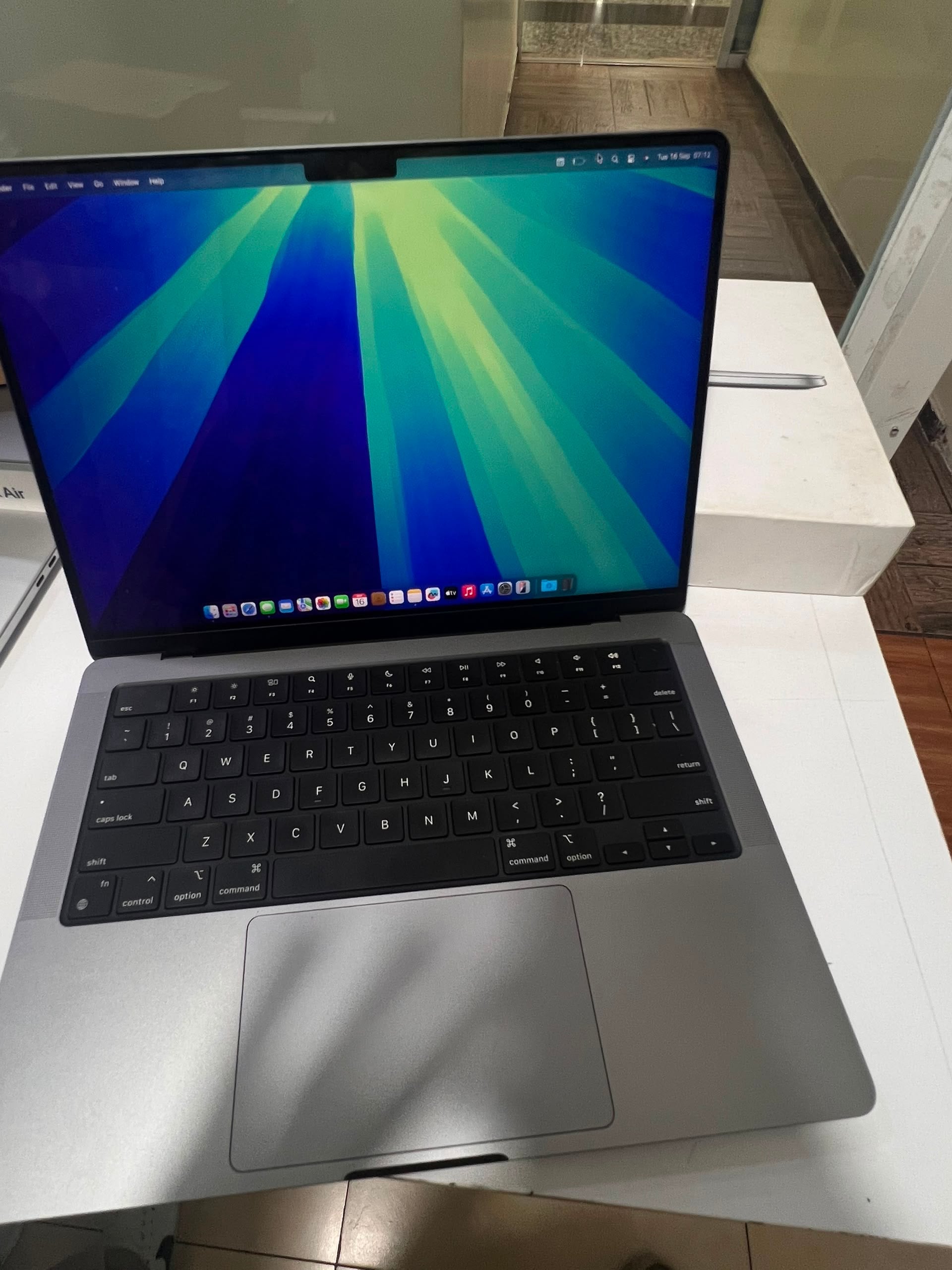 Open MacBook on a white surface showing the colorful macOS abstract wallpaper